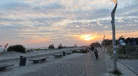 夕暮れ間近の浜辺を自転車で走る子供等